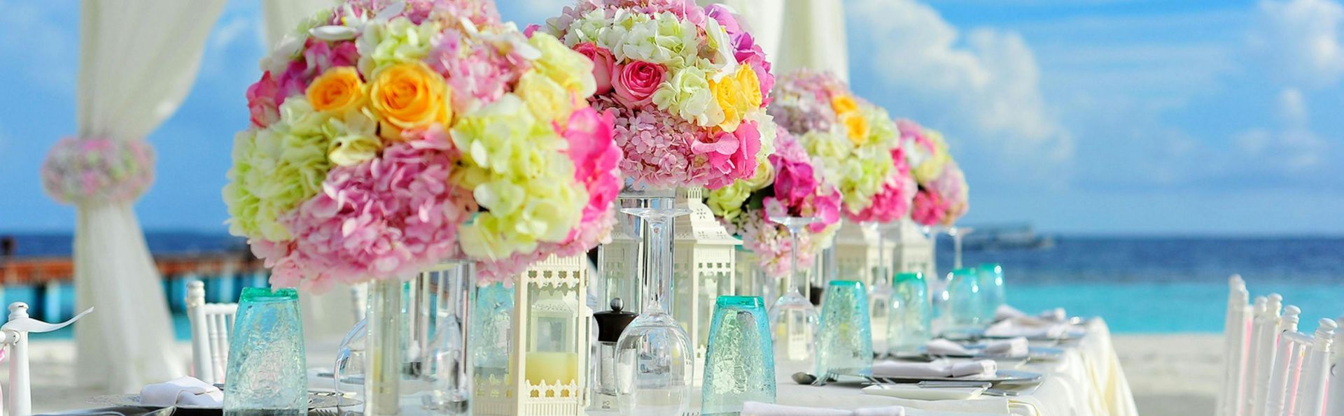 Beautiful seaside wedding setup with floral arrangements and pastel colors on a sunny day.