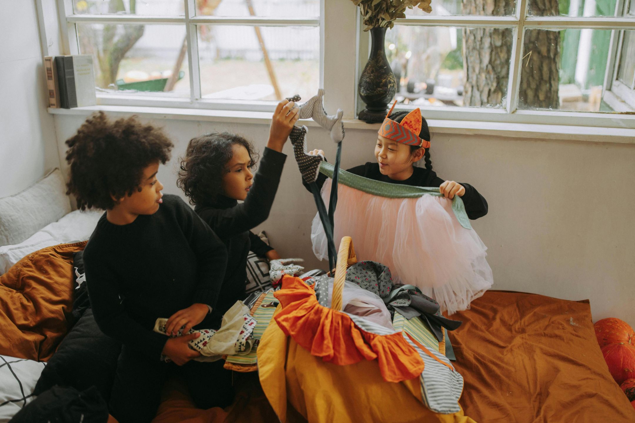 Three children playing with costumes indoors, celebrating Halloween with fun and creativity.