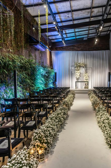 Beautifully decorated wedding venue with aisle, chairs and floral arrangements indoors.